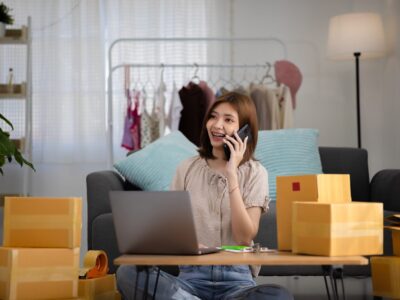 Smiling happy young Asian woman entrepreneur receiving phone cal