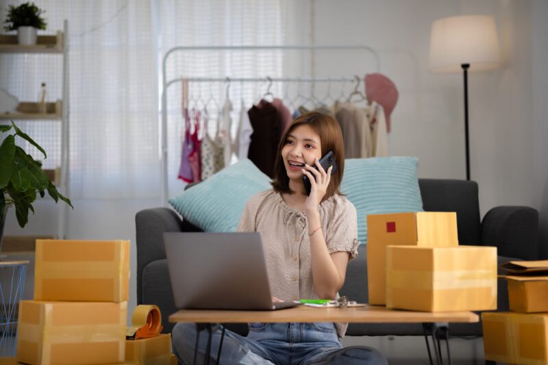 Smiling happy young Asian woman entrepreneur receiving phone cal